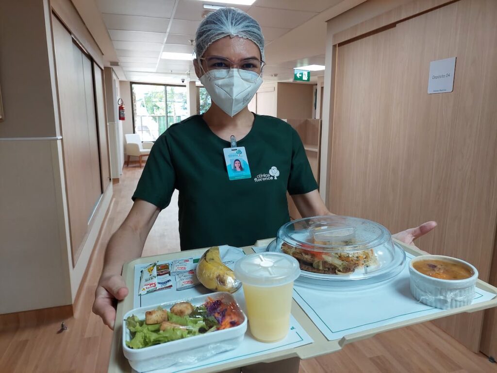 Nutricionista levando a refeição para pacientes em reabilitação pós UTI.